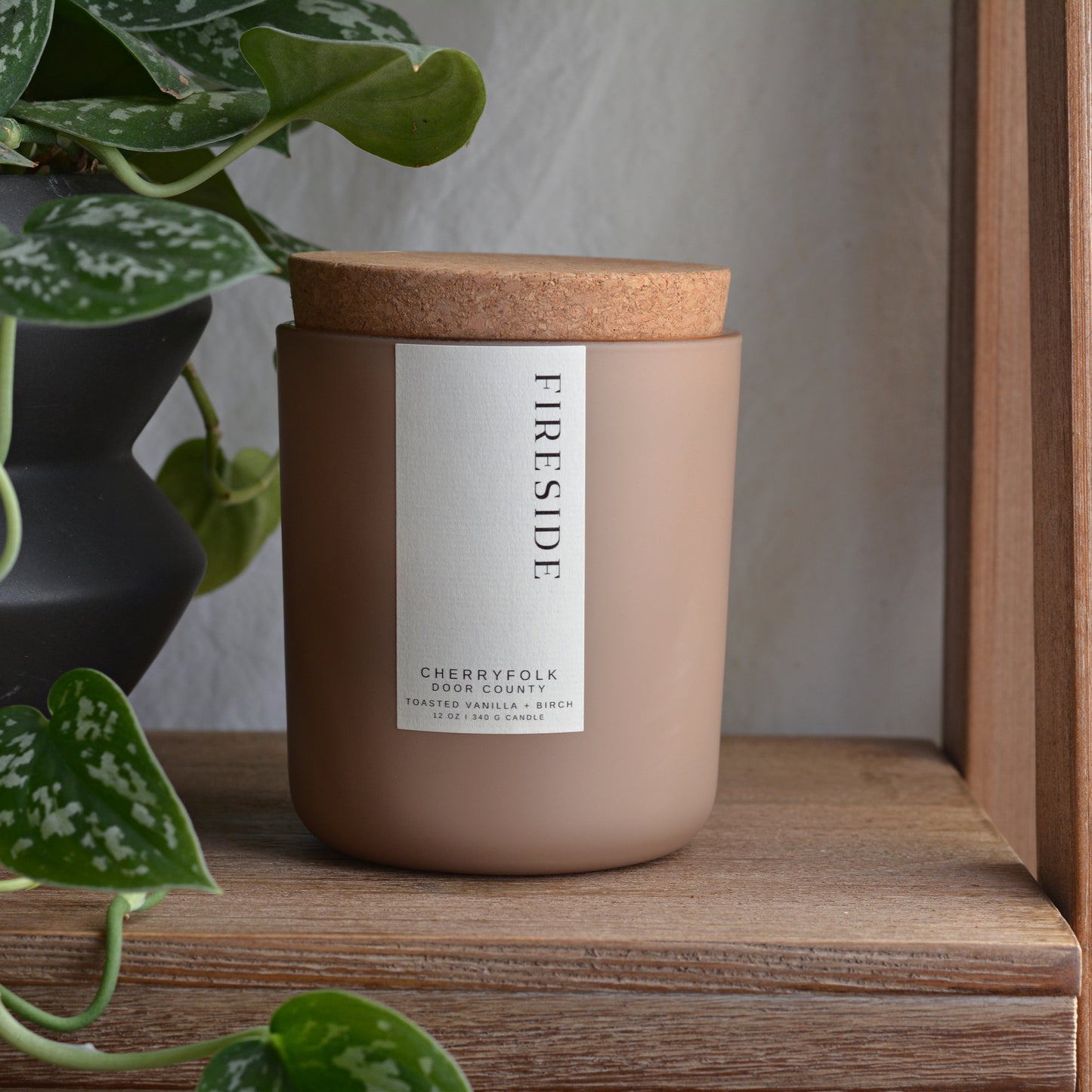a scented candle in a matte sage colored glass jar labeled with a sweet pine forest fragrance