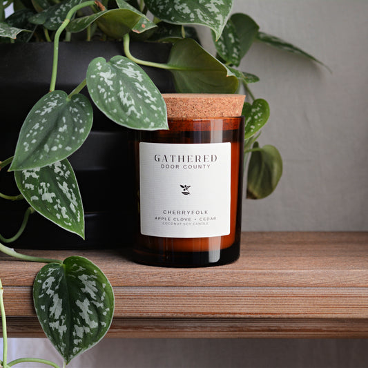 a hand poured candle in an amber glass jar with a cork lid