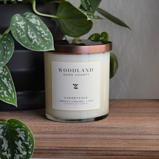 woodland scented candle in a clear glass jar with bronze copper lid